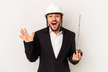 Miğfer takan ve taksimetre tutan genç mimar gri arka planda hoş bir sürpriz yaşıyor, heyecanlı ve el kaldırıyor..