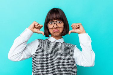 Mavi arka planda soyutlanmış genç melez kadın gururlu ve kendinden emin hissediyor, örnek olarak..