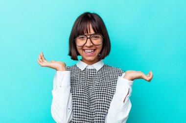 Mavi arka planda izole edilmiş genç melez kadın hoş bir yüz ifadesi sergiliyor..