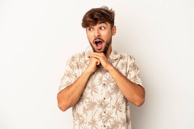 Genç melez adam gri arka planda izole edilmiş şans için dua ediyor, şaşırmış ve ağzı açık bir şekilde önüne bakıyor..