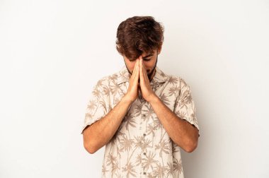 Genç melez adam gri arka planda izole edilmiş dua ediyor, bağlılık gösteriyor, dindar biri ilahi ilham arıyor..