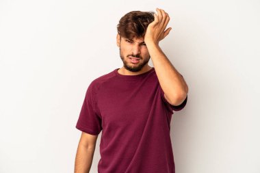 Genç melez adam gri arka planda izole edilmiş bir şekilde bir şeyi unutuyor. Alnına avuç içi ve kapalı gözlerle vuruyor..