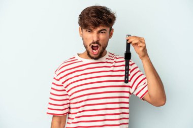 Mavi arka planda izole edilmiş bir kol saati tutan genç melez adam çok sinirli ve agresif bağırıyor..