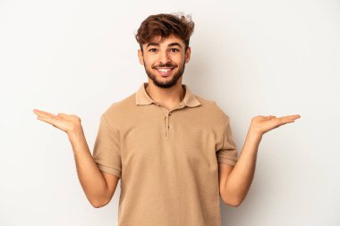 Gri arka planda soyutlanmış genç melez adam kollarıyla ölçeği yapıyor, mutlu ve kendinden emin hissediyor..