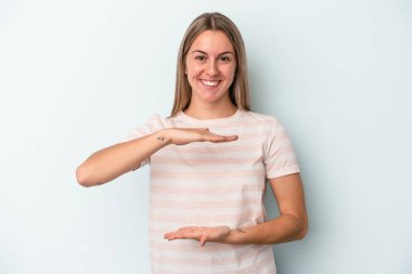 Mavi arka planda izole edilmiş beyaz bir kadın iki eliyle bir şey tutuyor, ürün sunumu..