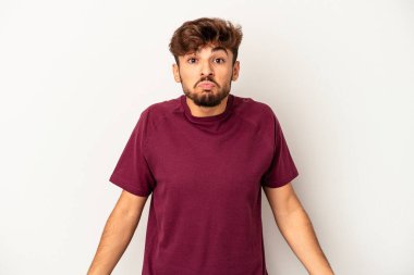 Genç melez adam, gri arka planda izole edilmiş omuzlarını silkmiş ve gözleri açık kalmış..