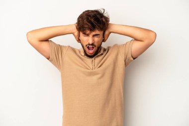 Genç melez adam, gri arka planda izole edilmiş kulakları kulaklarıyla kapatıyor ve çok fazla ses duymamaya çalışıyor..