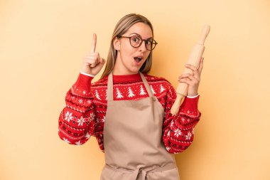 Genç fırıncı kadın, sarı arka planda izole edilmiş Noel için kurabiye yapıyor. Bir fikri var, ilham verici bir kavram..