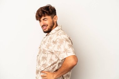 Genç melez adam gri arka planda izole edilmiş sırt ağrısı çekiyor..