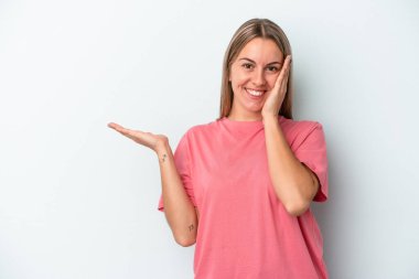 Mavi arka planda izole edilmiş beyaz bir kadın avuç içinde fotokopi alanı tutuyor, el üstünde tutuyor. Şaşırmış ve mutlu..