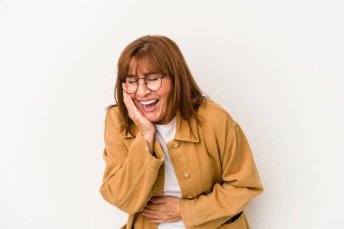 Beyaz arka planda izole edilmiş orta yaşlı beyaz kadın mutlu bir şekilde gülüyor ve ellerini karnının üstünde tutarak eğleniyor..