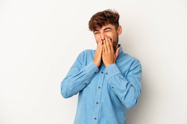 Genç melez adam gri arka planda izole edilmiş bir şekilde bir şeylere gülüyor, ağızlarını ellerle kapatıyor..