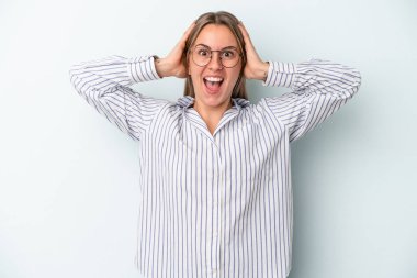 Mavi arka planda izole edilmiş genç beyaz kadın çığlık atıyor, çok heyecanlı, tutkulu, bir şeyden memnun..