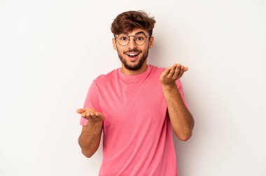 Gri arka planda soyutlanmış genç melez adam kollarıyla ölçeği yapıyor, mutlu ve kendinden emin hissediyor..