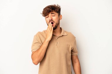 Genç melez adam gri arka planda izole edilmiş esniyor. Ağzı eliyle kapatan yorgun bir jest gösteriyor..