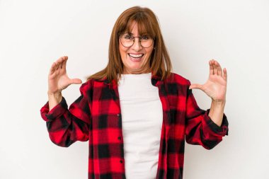 Beyaz arka planda izole edilmiş orta yaşlı beyaz kadın elinde avuç içi bir şeyle kameraya sunuyor..