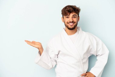 Mavi arka planda karate yapan genç melez avuçta fotokopi alanı ve belinde bir el daha olduğunu gösteriyor..