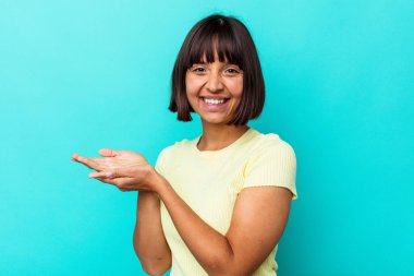 Mavi arka planda izole edilmiş genç melez bir kadın avucunun içinde bir kopyasını tutuyor..