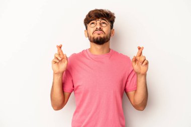 Genç melez adam, gri arka planda izole edilmiş şans dilemek için şans diliyor.