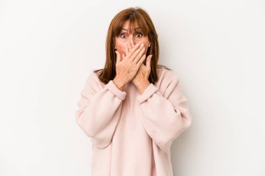 Beyaz arka planda izole edilmiş orta yaşlı beyaz kadın elleriyle ağzını kapatırken şok oldu..