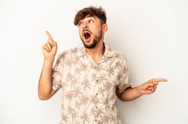 Genç melez adam gri arka planda izole edilmiş farklı kopya alanlarını gösteriyor, birini seçiyor, parmaklarıyla gösteriyor..