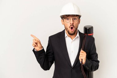 Gri arka planda izole edilmiş kask takan genç mimar yan tarafı işaret ediyor.