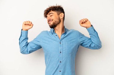 Genç melez adam, gri arka planda izole edilmiş, kollarını uzatmış, rahat bir konumda..