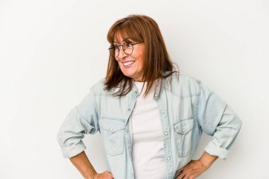 Beyaz arka planda izole edilmiş orta yaşlı beyaz kadın mutlu bir şekilde gülüyor ve ellerini karnının üstünde tutarak eğleniyor..