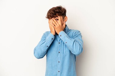 Genç melez adam gri arka planda izole edilmiş parmaklarıyla kameraya göz kırpıyor, yüzünü kapatmaktan utanıyor..