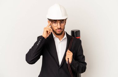 Gri arka planda izole edilmiş bir kask takan genç mimar parmağıyla tapınağı işaret ediyor, düşünüyor ve bir göreve odaklanıyor..