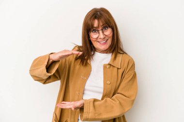 Beyaz arka planda izole edilmiş orta yaşlı beyaz bir kadın. Elinde parmakları olan, gülümseyen ve kendinden emin bir şey var..