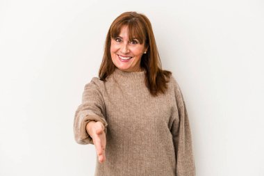 Beyaz arka planda izole edilmiş orta yaşlı beyaz kadın selamlaşma jesti olarak kameraya elini uzatıyor..