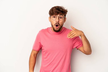 Genç melez adam gri arka planda izole edilmiş bir şekilde bir şeylere gülüyor, ağızlarını ellerle kapatıyor..