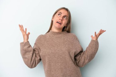 Mavi arka planda izole edilmiş genç beyaz kadın gökyüzüne haykırıyor, yukarı bakıyor, hayal kırıklığına uğramış..