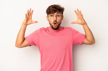 Genç melez adam gri arka planda bir zaferi ya da başarıyı kutlarken şaşırdı ve şok oldu..