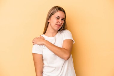 Sarı arka planda izole edilmiş, omuz ağrısı olan beyaz bir kadın..