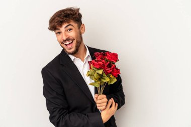 Young mixed race man holding bouquet of roses isolated on white background laughing and having fun.