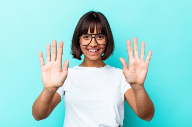 Mavi arka planda izole edilmiş genç melez kadın on numarayı elleriyle gösteriyor..