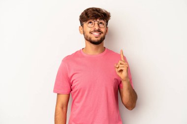 Genç melez adam gri arka planda izole edildi. İki parmağı da boş bir alan gösteriyor..