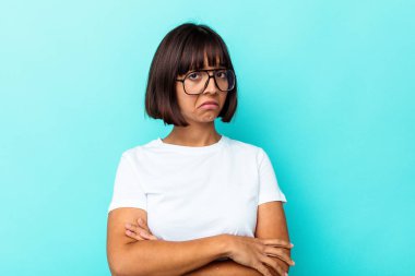 Mavi arka planda izole edilmiş genç, melez bir kadın kameraya alaycı bir ifadeyle bakıyor..