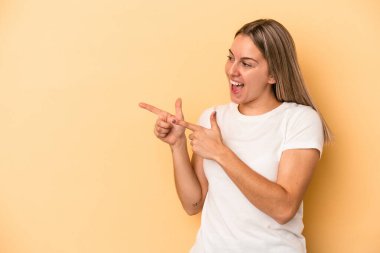 Sarı arka planda izole genç beyaz kadın başparmak uzakta, gülüyor ve kaygısız.