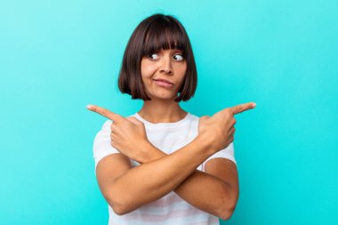 Mavi arka plan noktalarında izole edilmiş genç melez kadın iki seçenek arasında seçim yapmaya çalışıyor..