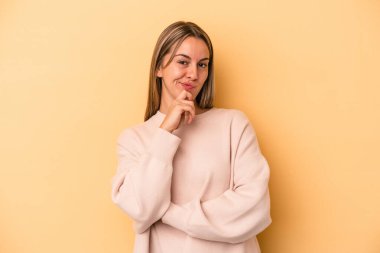 Kafkasyalı genç bir kadın sarı arka planda izole edilmiş düşünüyor ve yukarı bakıyor, yansıtıyor, düşünüyor, hayal kuruyor..