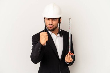 Miğfer takan ve taksimetre tutan genç bir mimar gri arka planda kameraya yumruk, agresif yüz ifadesi gösteriyor..