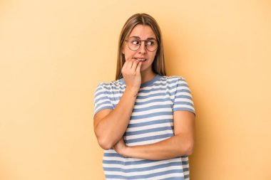 Sarı arka planda izole edilmiş, tırnak yiyen, gergin ve endişeli bir beyaz kadın..