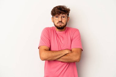 Gri arka planda izole edilmiş genç melez adamın yanakları şişer, yorgun bir ifadesi vardır. Yüz ifadesi kavramı.