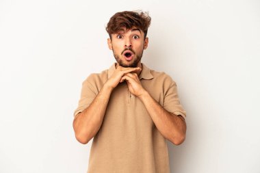 Genç melez adam gri arka planda izole edilmiş şans için dua ediyor, şaşırmış ve ağzı açık bir şekilde önüne bakıyor..