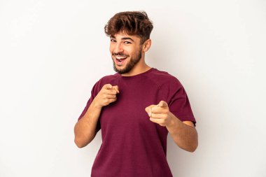 Gri arka planda izole edilmiş genç melez adam parmaklarıyla ön tarafı işaret ediyor..