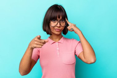 Mavi arka planda izole edilmiş genç melez bir kadın şakağı parmağıyla işaret ediyor, düşünüyor ve bir göreve odaklanıyor..
