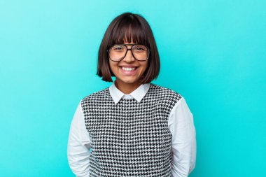 Mavi arka planda izole edilmiş genç melez kadın mutlu, güler yüzlü ve neşeli..